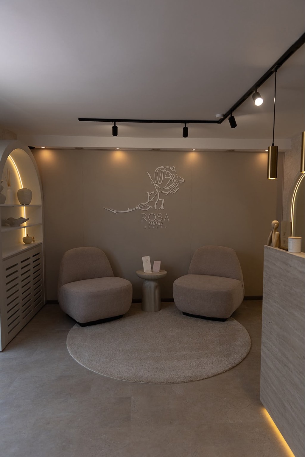 Empfangsbereich von Rosamina Beauty mit zwei Sesseln und Wandlogo.